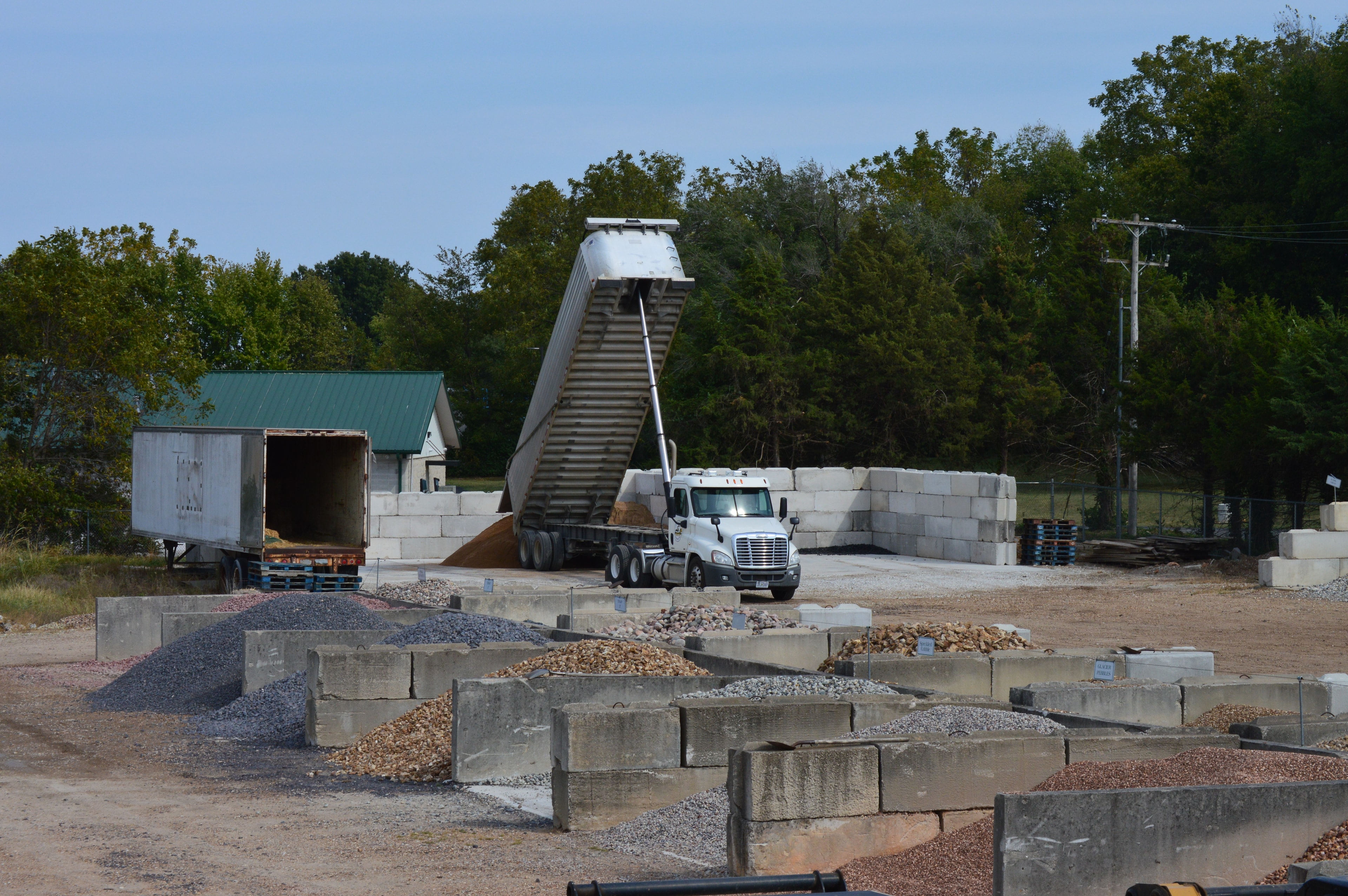 Semi truck dumping a load at the Load & Go yard with full gravel bin selection visible